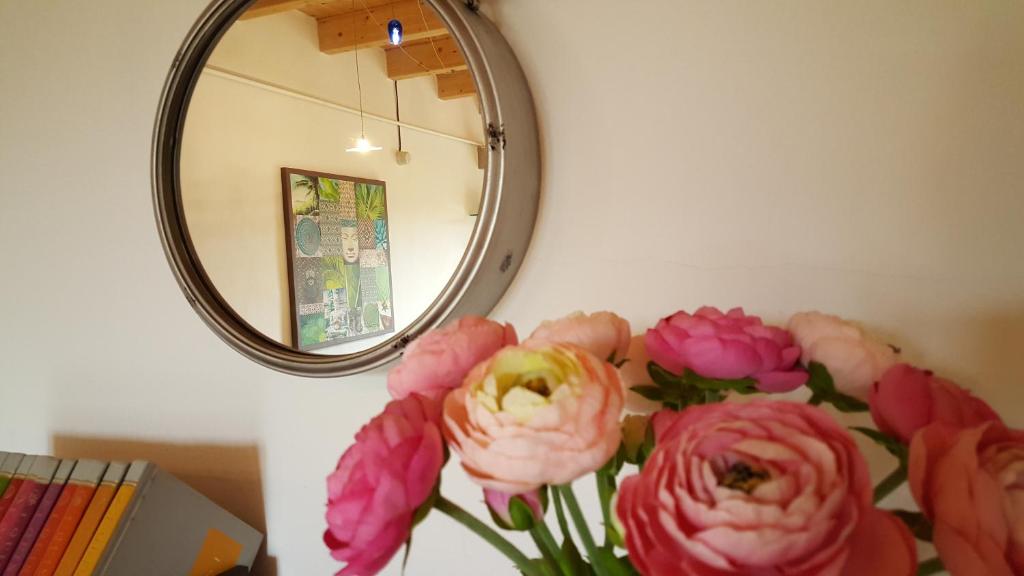 un vaso di fiori rosa di fronte a uno specchio di Casa Di Arianna a Ferrara