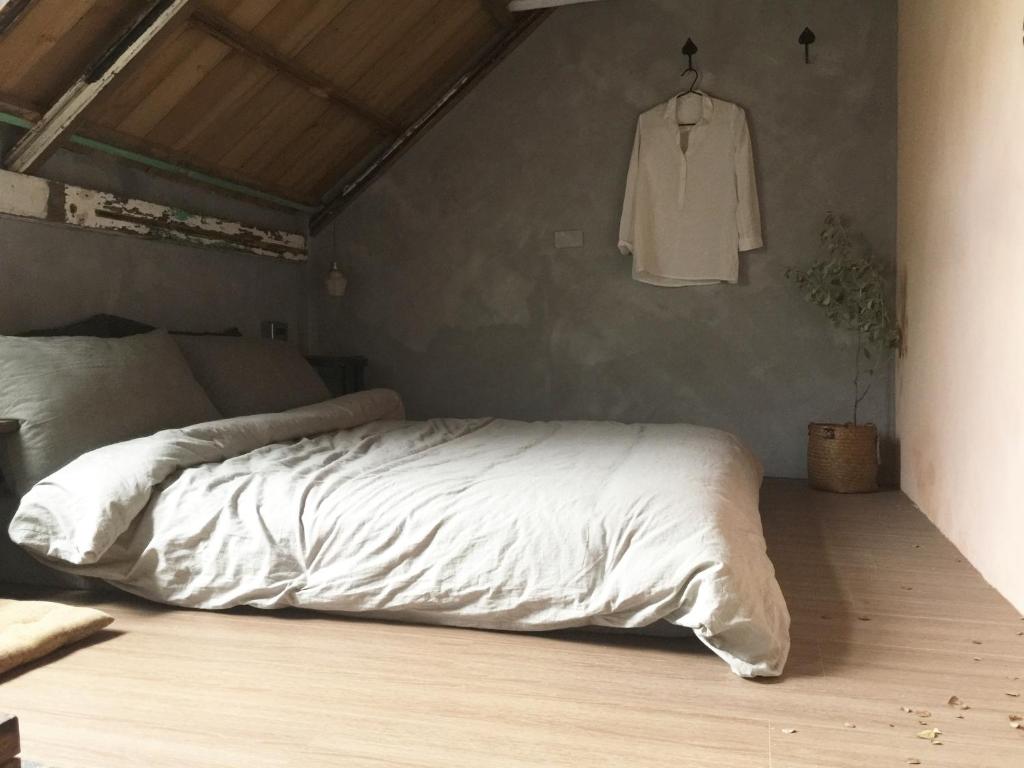 a bedroom with a white bed and a shirt hanging on the wall at MIAOKO Hostel in Dahan