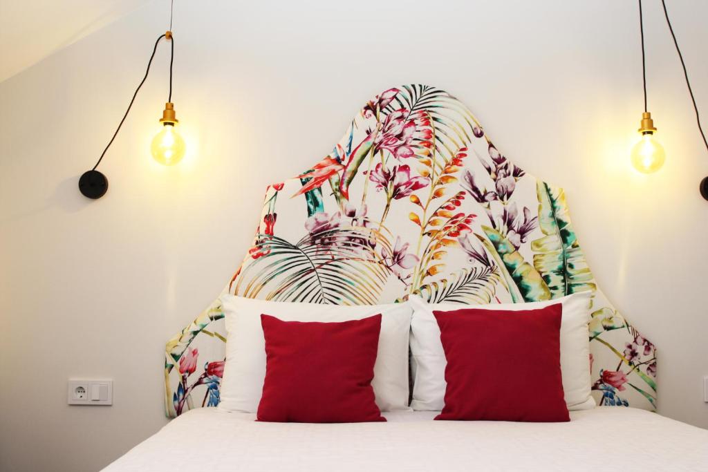 ein Bett mit roten Kissen und einem floralen Kopfteil in der Unterkunft Vilnius Apartments in Vilnius