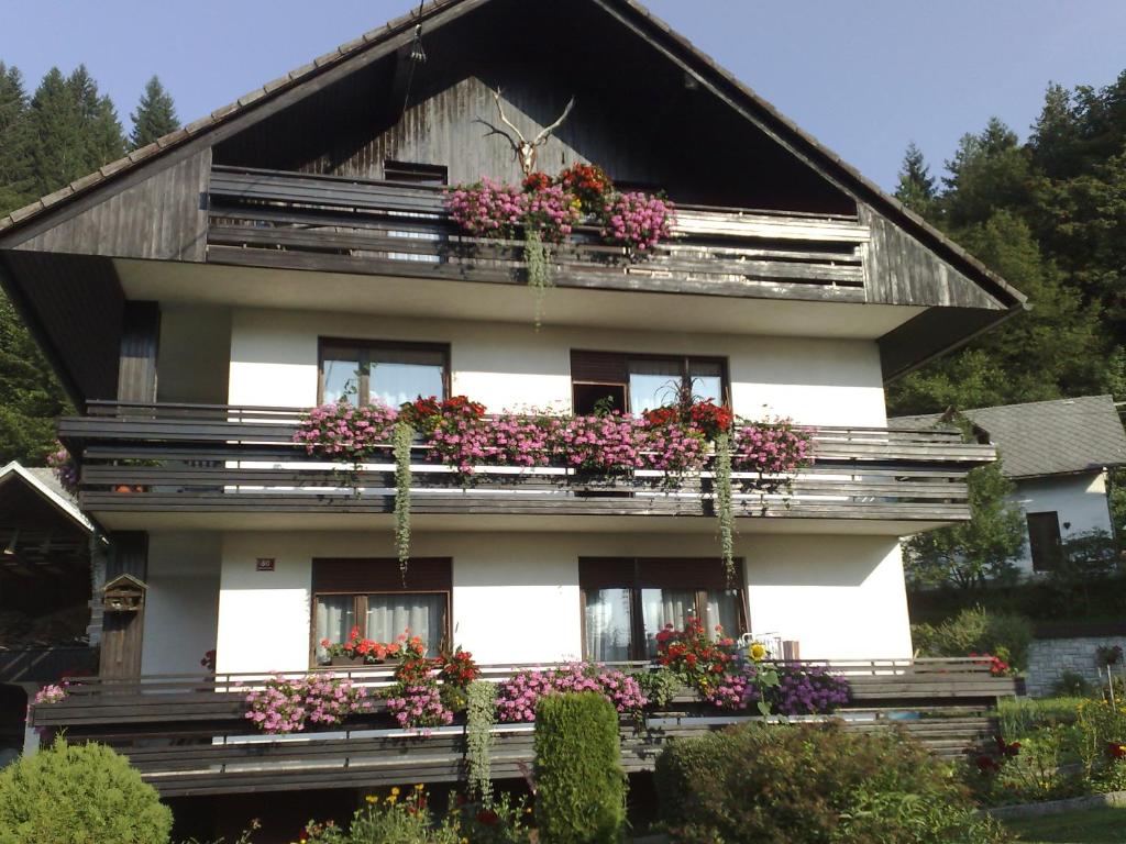 une maison avec des boîtes de fleurs sur ses fenêtres dans l'établissement Apartment KLEMEN, à Bohinjska Bela