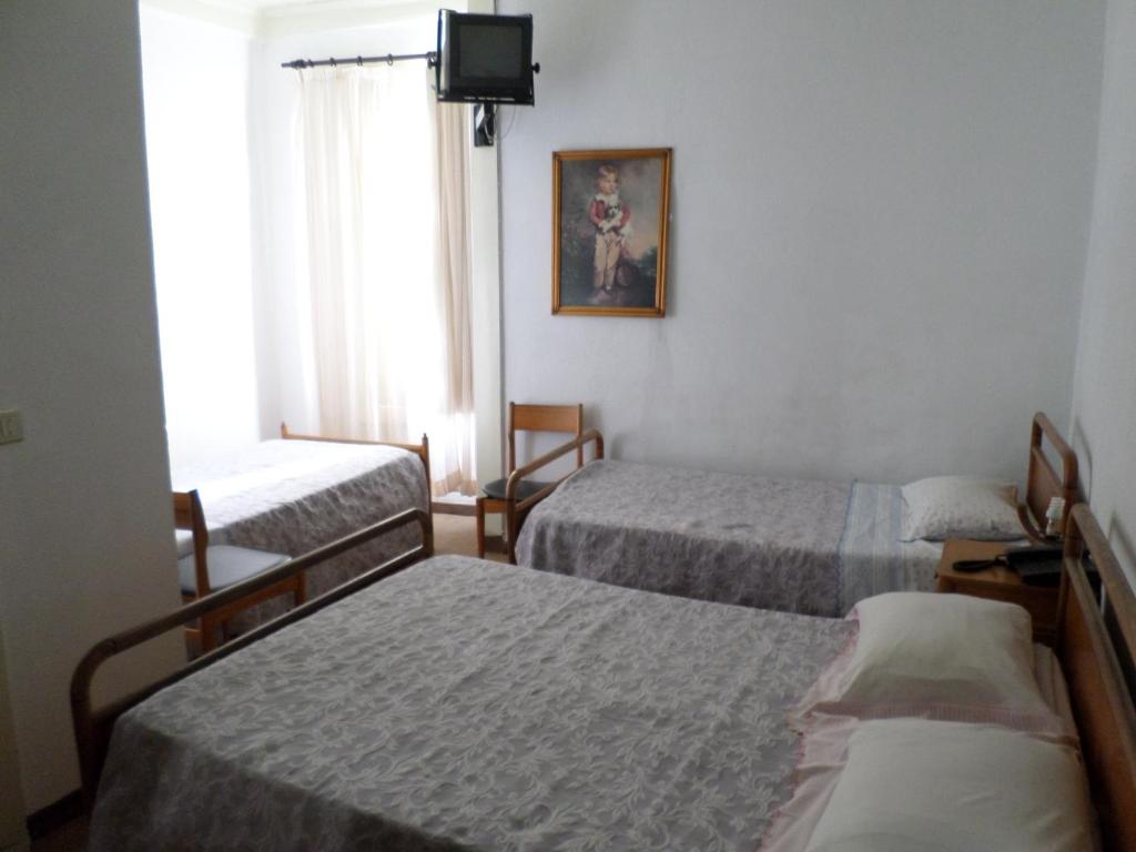 a hotel room with three beds and a tv at Rustico & Singelo - Hotelaria e Restauração, Lda in Vila Real