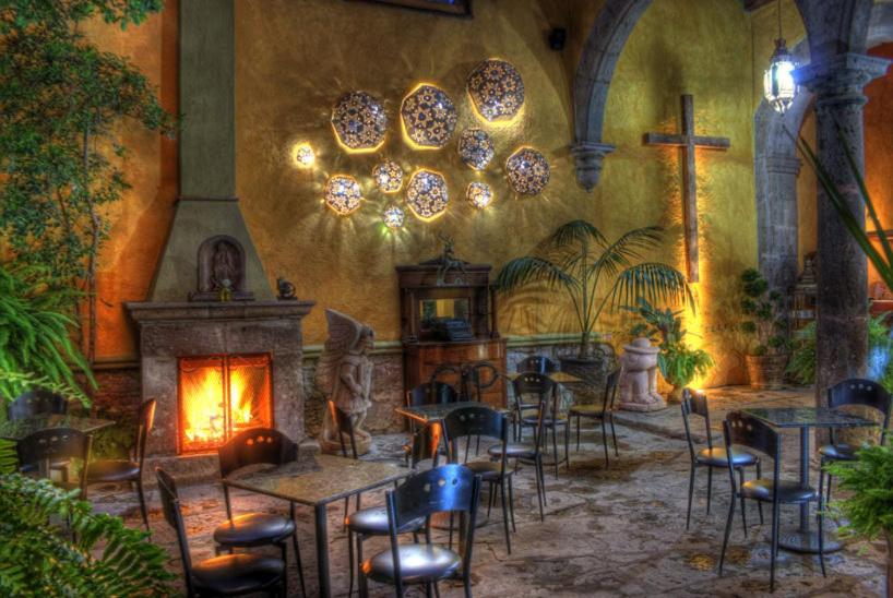 a restaurant with tables and chairs and a fireplace at Hotel Casa del Anticuario in Morelia