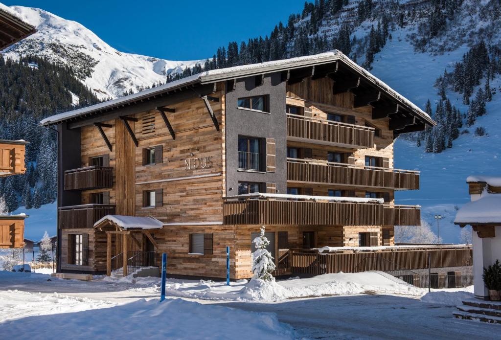 a log cabin in the snow with a mountain at Nidus Luxury Apartments in Lech am Arlberg