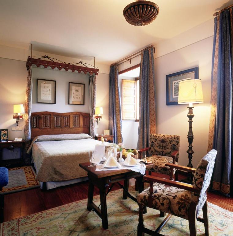 a bedroom with a bed and a table and a chair at Parador de Santiago - Hostal Reis Catolicos in Santiago de Compostela