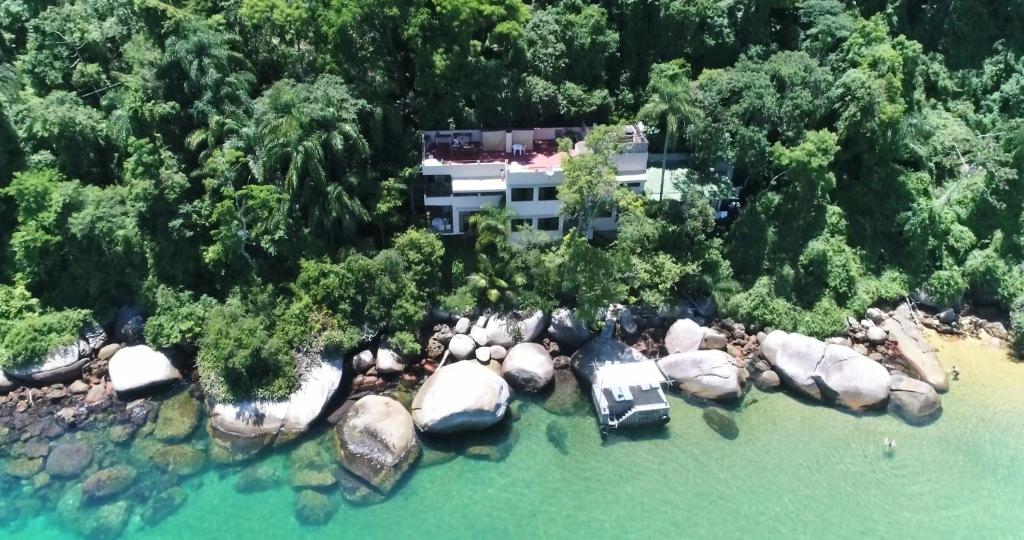 an aerial view of a house with rocks in the water at Vila Pedra Mar in Praia Vermelha