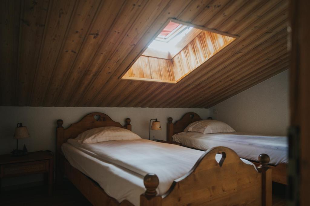 two beds in a room with a skylight at Hôtel Magrappé in Veysonnaz