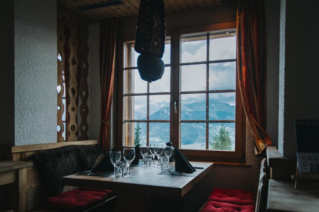 a table with wine glasses and a window in a restaurant at Hôtel Magrappé in Veysonnaz