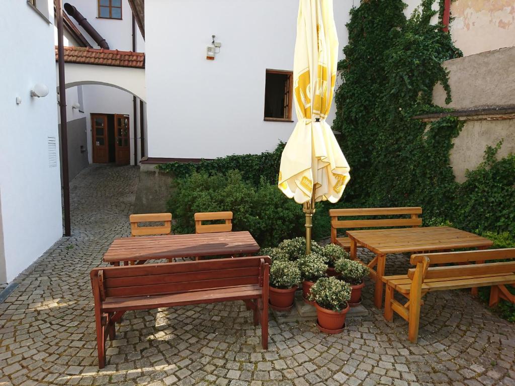 eine Terrasse mit zwei Holzbänken und einem gelben Regenschirm in der Unterkunft Hotel U Růže in Slavonice