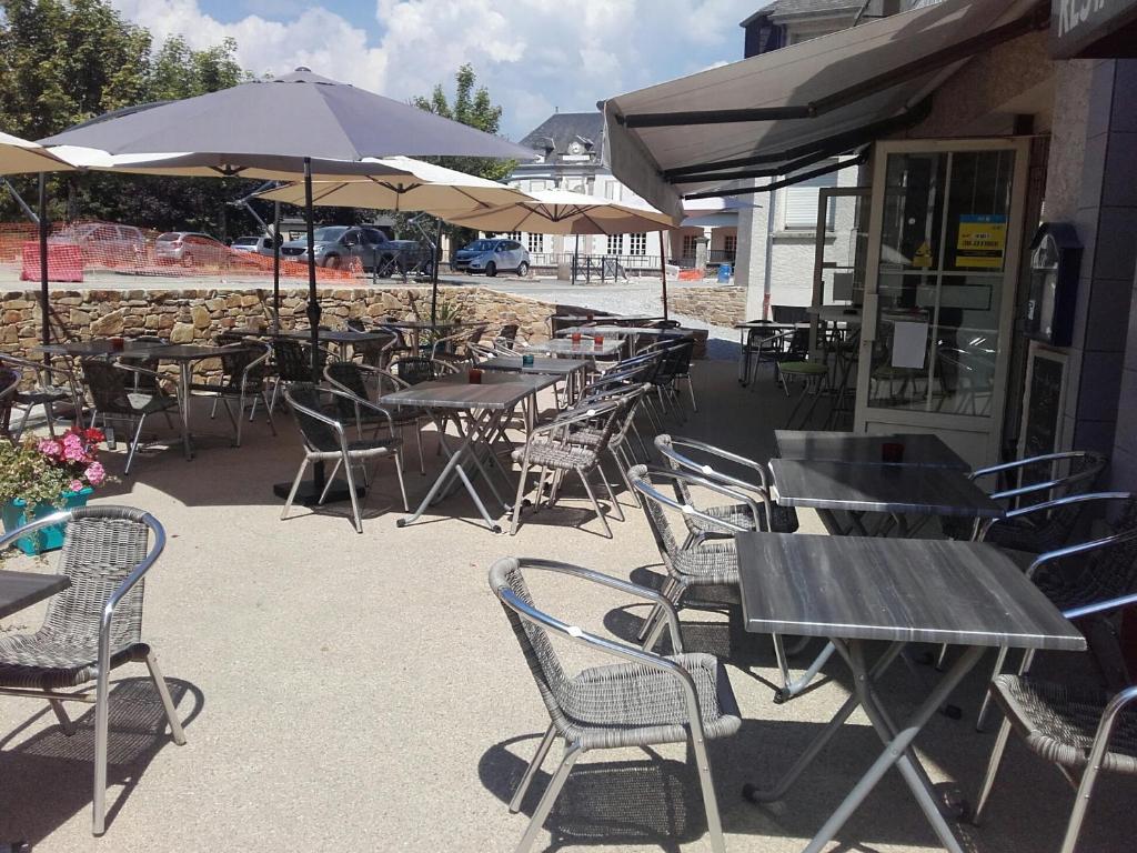 un patio extérieur avec des tables, des chaises et des parasols dans l'établissement L'Oustal, à Naves