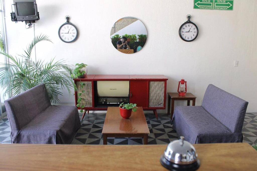 a living room with two chairs and a tv and clocks at Casa Zapopan Hotel in Guadalajara