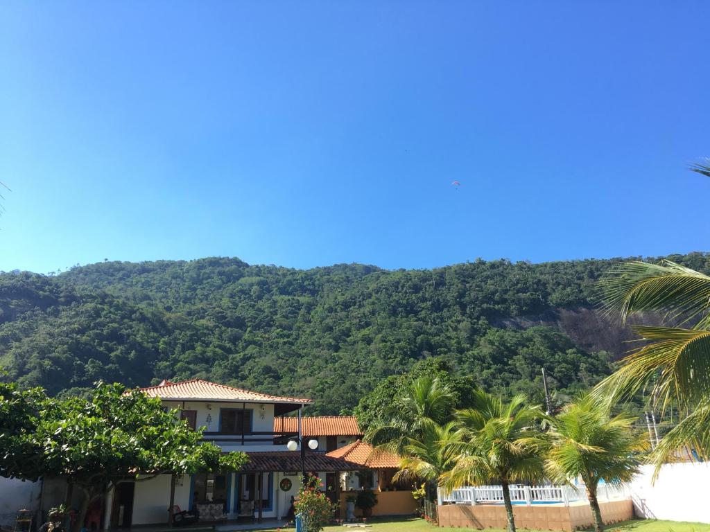 a house with palm trees in front of a mountain at Pousada Piratininga in Niterói