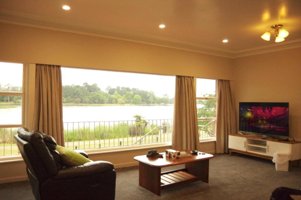 a living room with a couch and a large window at Lake Domain Boarding Holiday House in Hamilton