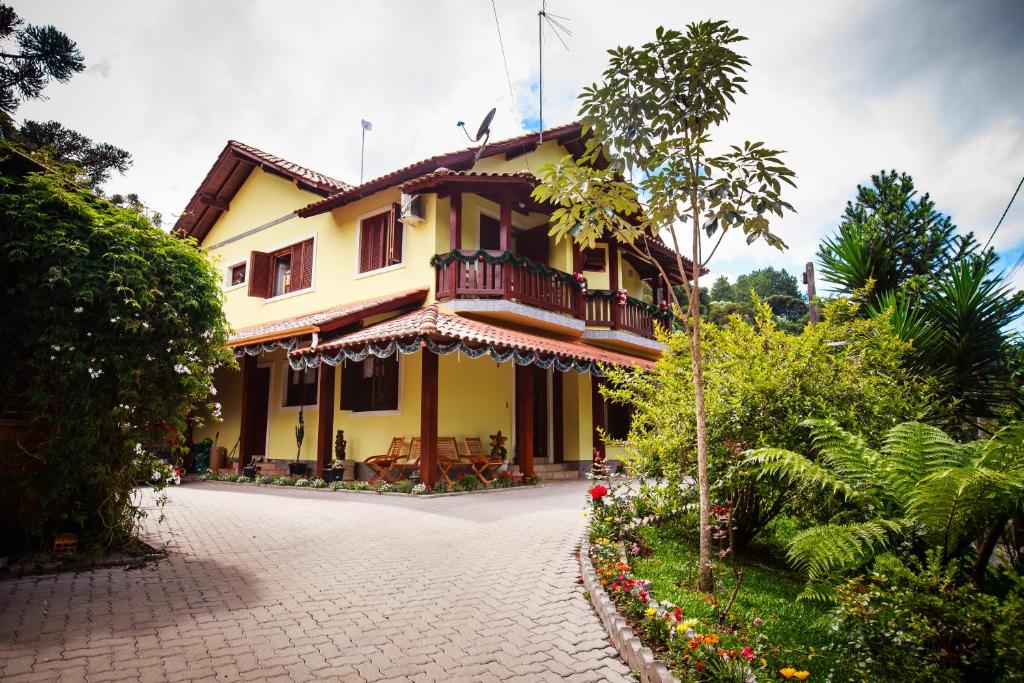 une maison jaune avec un balcon et une allée. dans l'établissement Pousada Unser Haus, à São Francisco de Paula