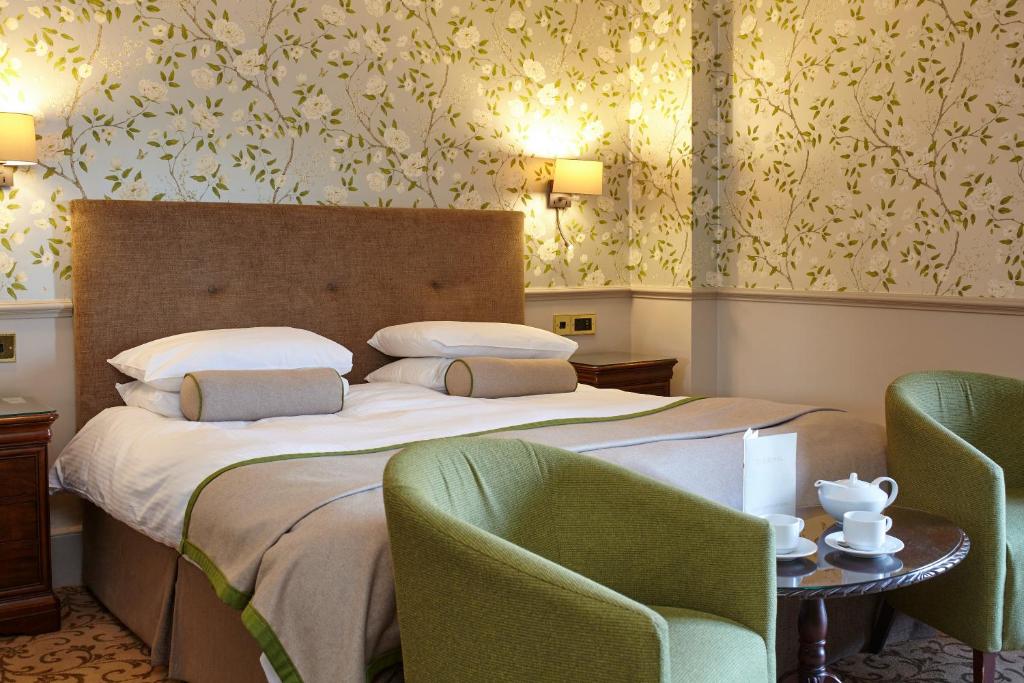 a bedroom with a bed with two chairs and a table at The Royal Hotel in Ventnor