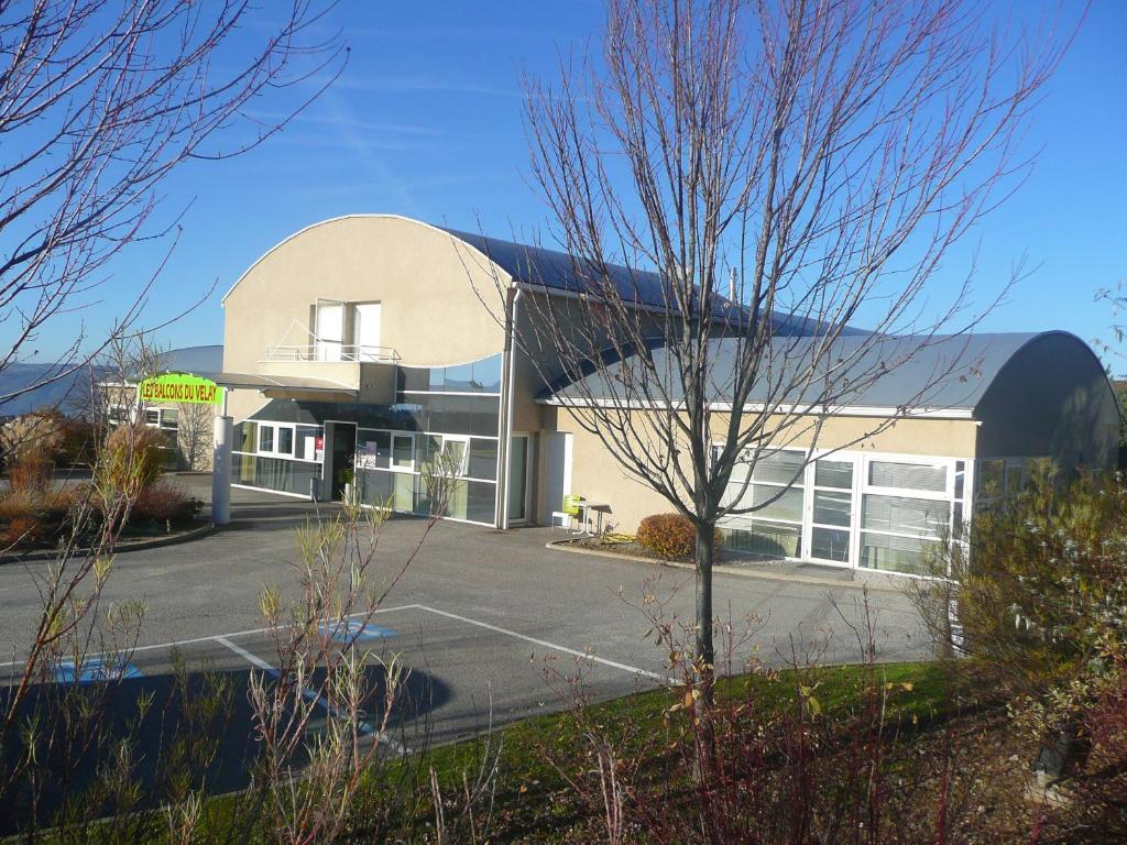 een groot wit gebouw met een zwart dak bij Les Balcons Du Velay in Monistrol-sur-Loire