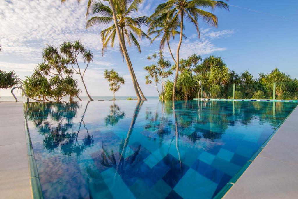 una piscina a sfioro con palme su una spiaggia di Ananya Beach Resort a Tangalle