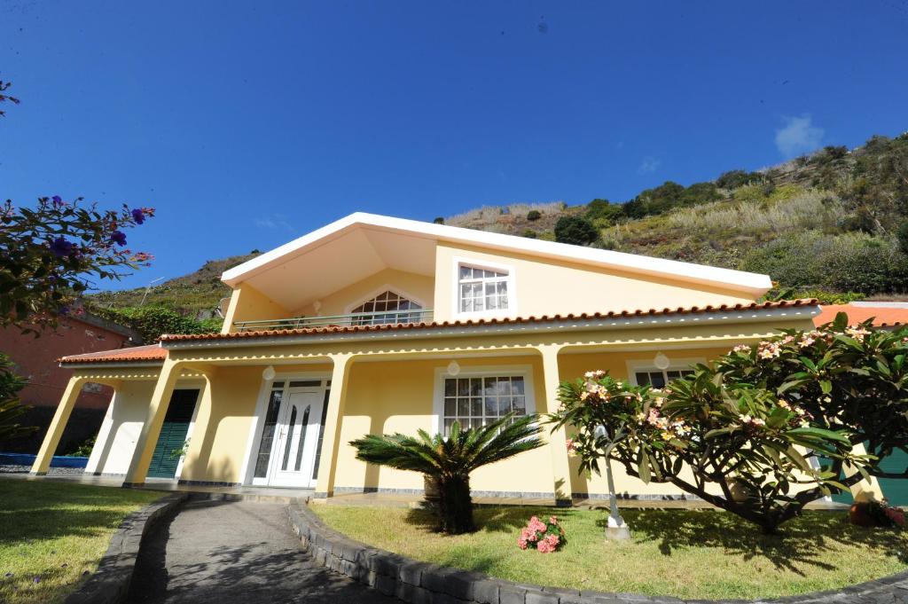 a yellow house with a hill in the background at Villa Atlântico in Ponta do Sol