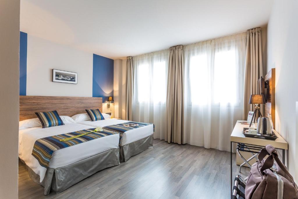 a hotel room with a bed and a desk and window at DWO Urban Granada in Granada