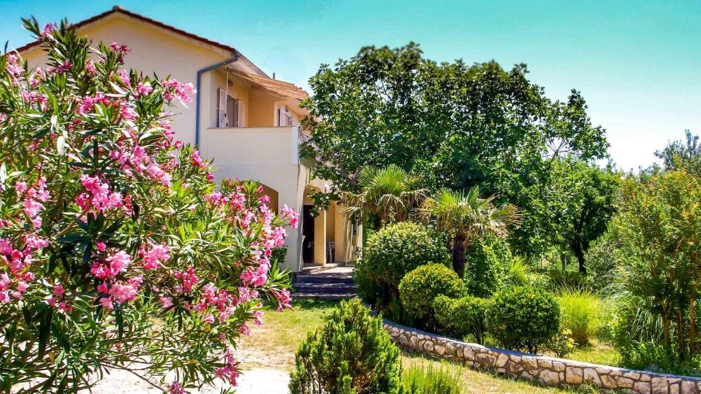 a house with pink flowers in front of it at Adria Arba Apartments in Rab
