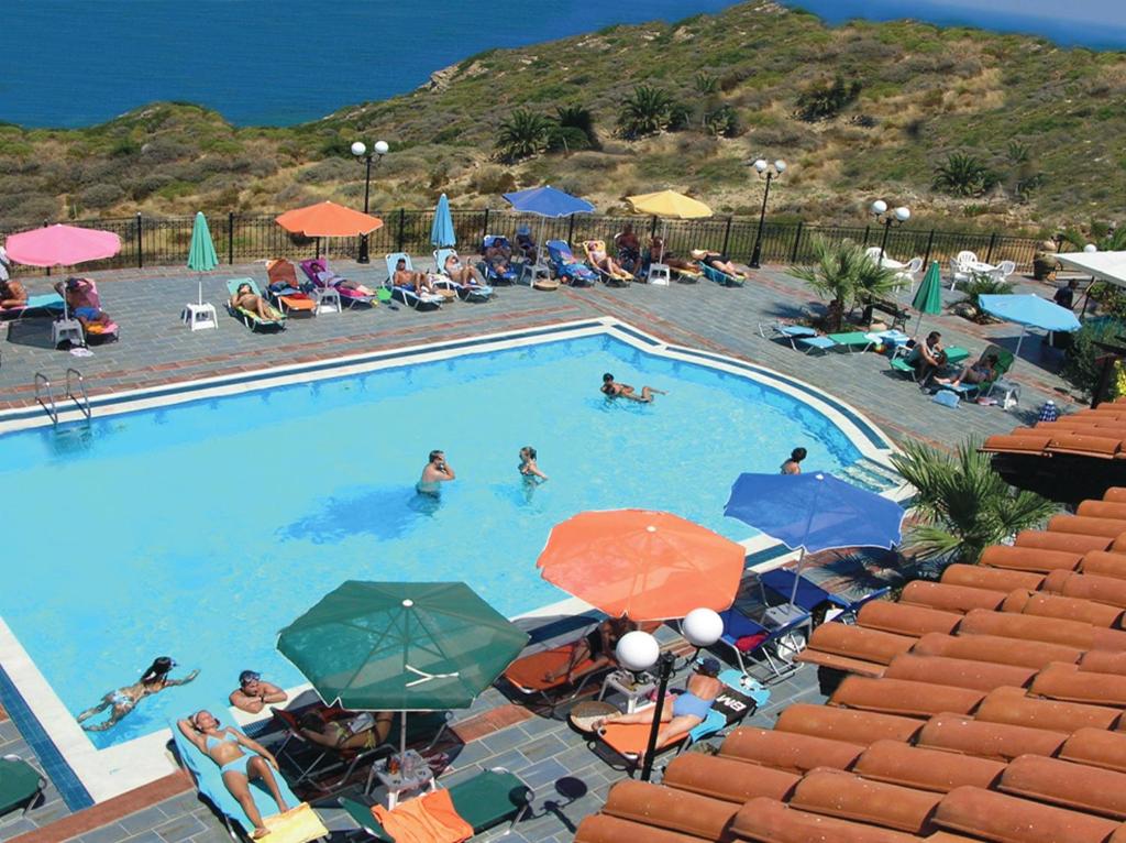 een groot zwembad met mensen in stoelen en parasols bij Pennystella Apartments in Agia Pelagia