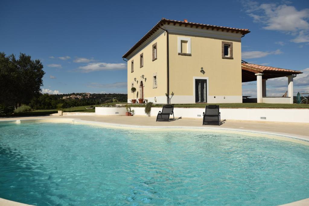 a villa with a swimming pool in front of a house at Tenuta Donna Caterina in Tessennano