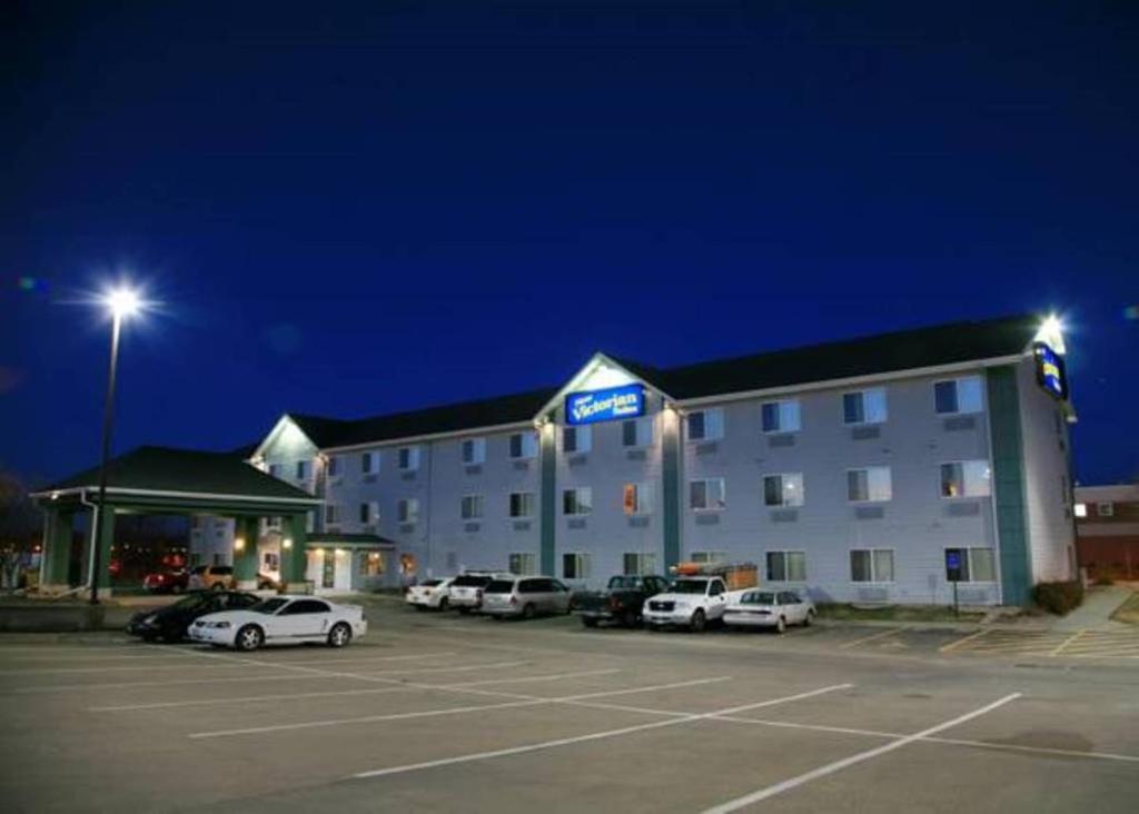 un hotel con coches estacionados en un estacionamiento por la noche en New Victorian Inn & Suites Lincoln, en Lincoln
