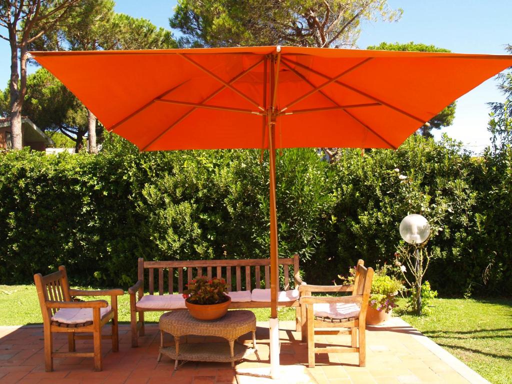een oranje paraplu naast een tafel en stoelen bij Villa Betty in Porto Clementino