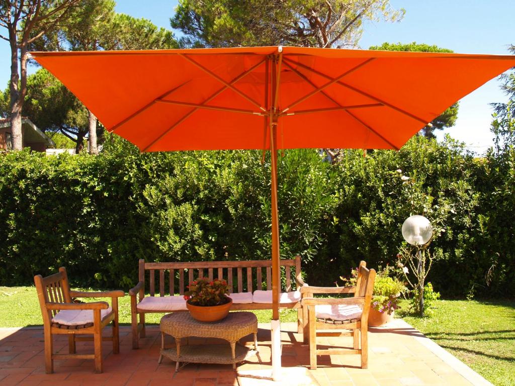 Porto ClementinoにあるVilla Bettyのテーブルと椅子の横に座るオレンジの傘