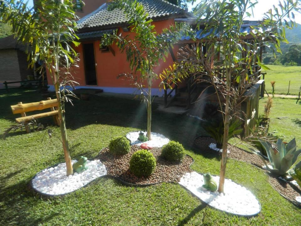 a garden with three potted trees and a house at Pousada Casa Fazenda do Rio in Visconde De Maua