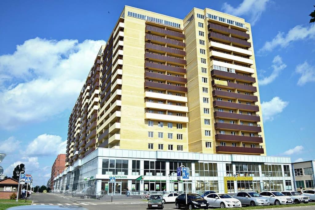 a large yellow building with cars parked in front of it at Apartments on Chkalova in Maykop