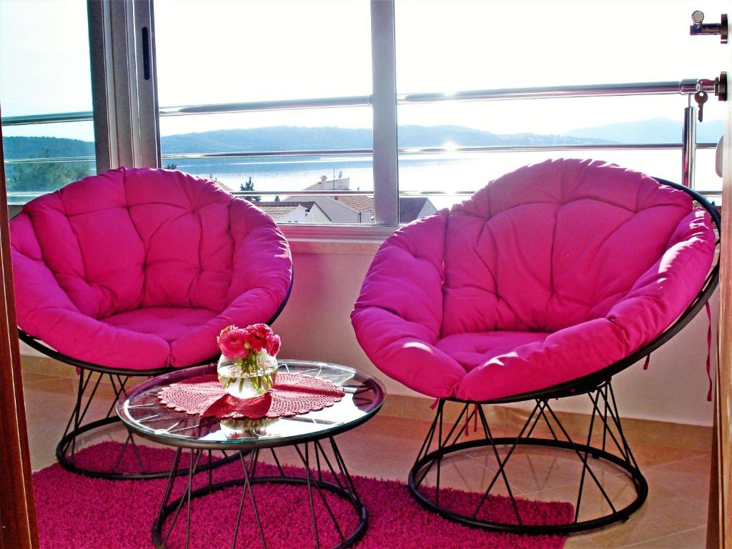 2 sillas rosas y una mesa frente a una ventana en Apartments Linda, en Trogir