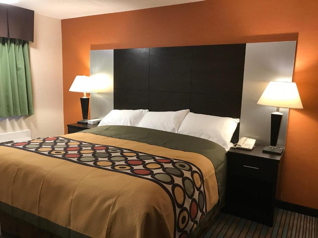 1 cama grande en una habitación de hotel con 2 lámparas en Bay Hill Inns & Suites, en Neepawa