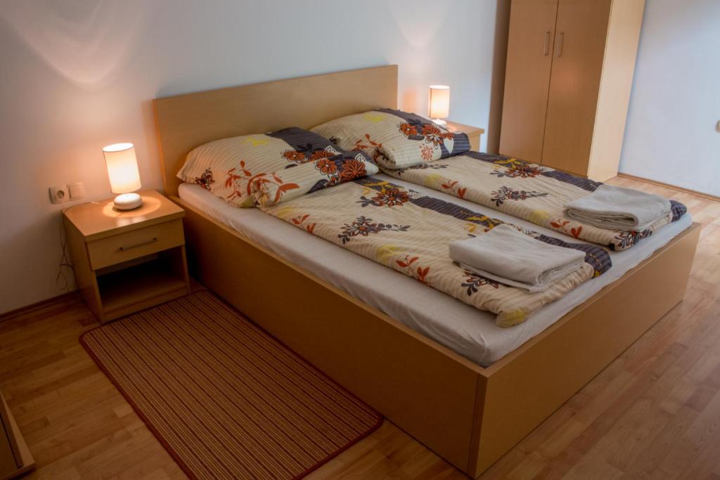 ホルトバージにあるSasfészek - Falusi szálláshelyのナイトスタンドとベッドサイドシックスが備わる客室のベッド1台分です。