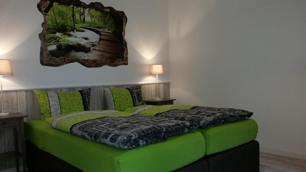 a bedroom with a green bed with two tables and two lamps at Mara in Lübeck