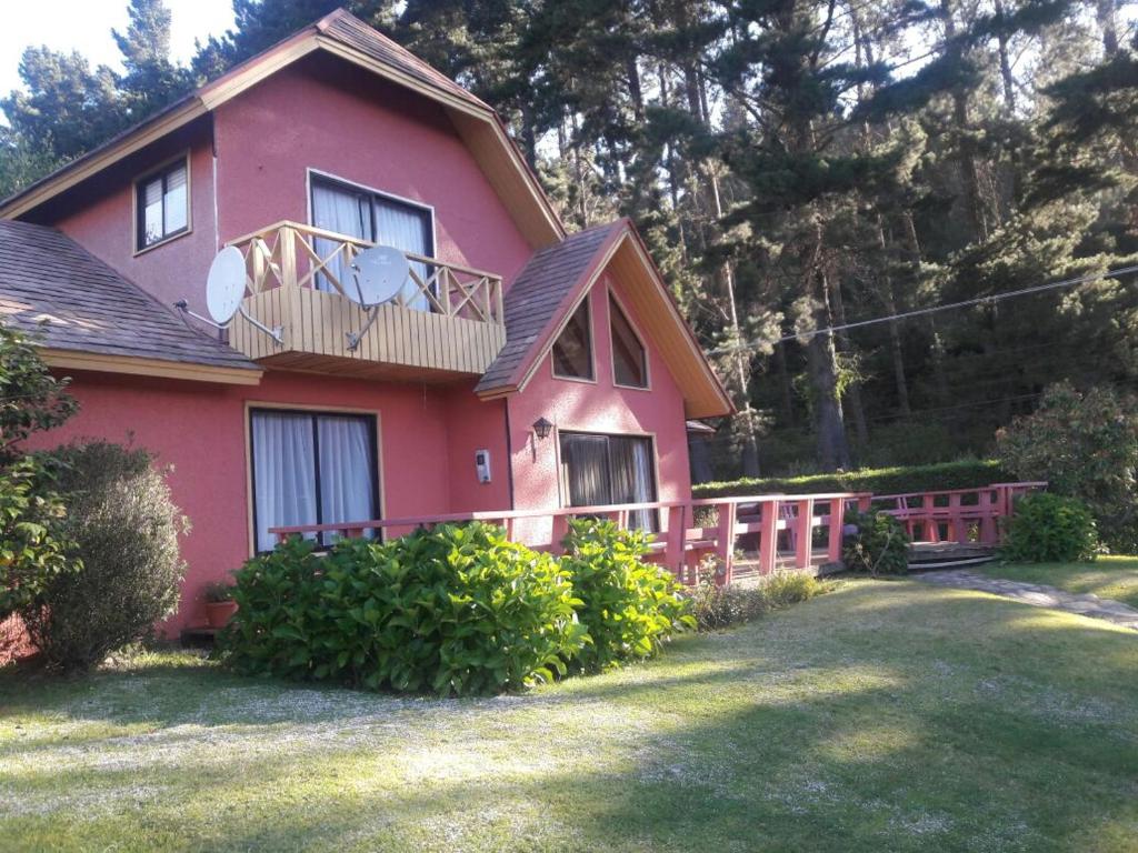 ein rosafarbenes Haus mit einer Veranda und einem Balkon in der Unterkunft Pingueral in Dichato