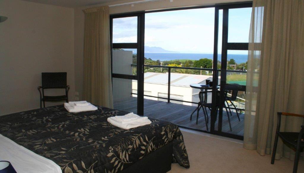 a bedroom with a bed and a view of a balcony at Leigh Apartments in Leigh