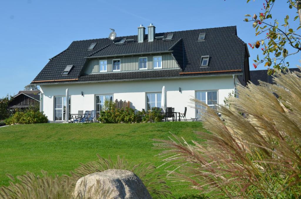 ein großes weißes Haus mit schwarzem Dach in der Unterkunft Haus Mönchgut - Haushälfte 2 "Findling" in Alt Reddevitz