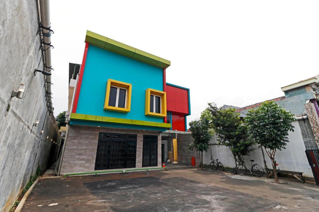 RedDoorz Plus near Halim Perdanakusuma 2 في جاكرتا: منزل ملون يقع على جانب المبنى