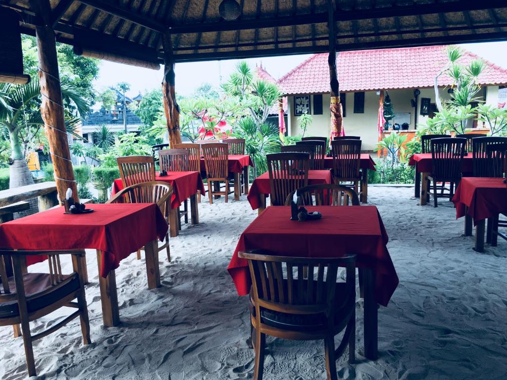un groupe de tables et de chaises avec un tissu de table rouge dans l'établissement Yudhist Guest House, à Nusa Lembongan