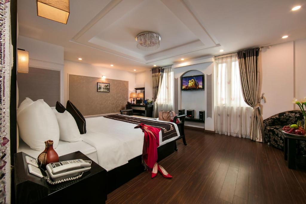 Hanoi Emotion Hotel في هانوي: غرفه فندقيه بسرير واريكه