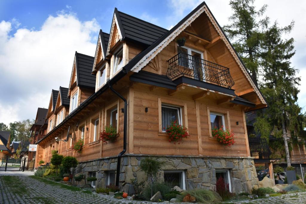 une maison en bois avec des fleurs devant elle dans l'établissement Pokoje Gościnne BENITA, à Zakopane