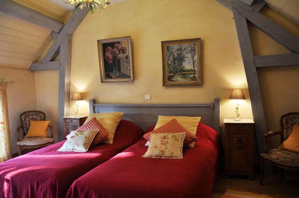 a bedroom with two beds with red sheets and pillows at Grange de la Herde in Camon