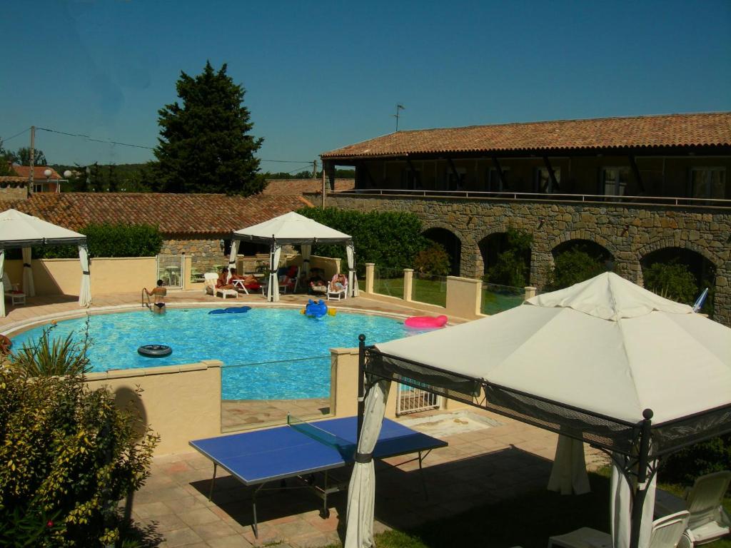 - une piscine avec un parasol à côté d&#39;un bâtiment dans l&#39;établissement Hôtel de la Madeleine à Tornac, à Tornac