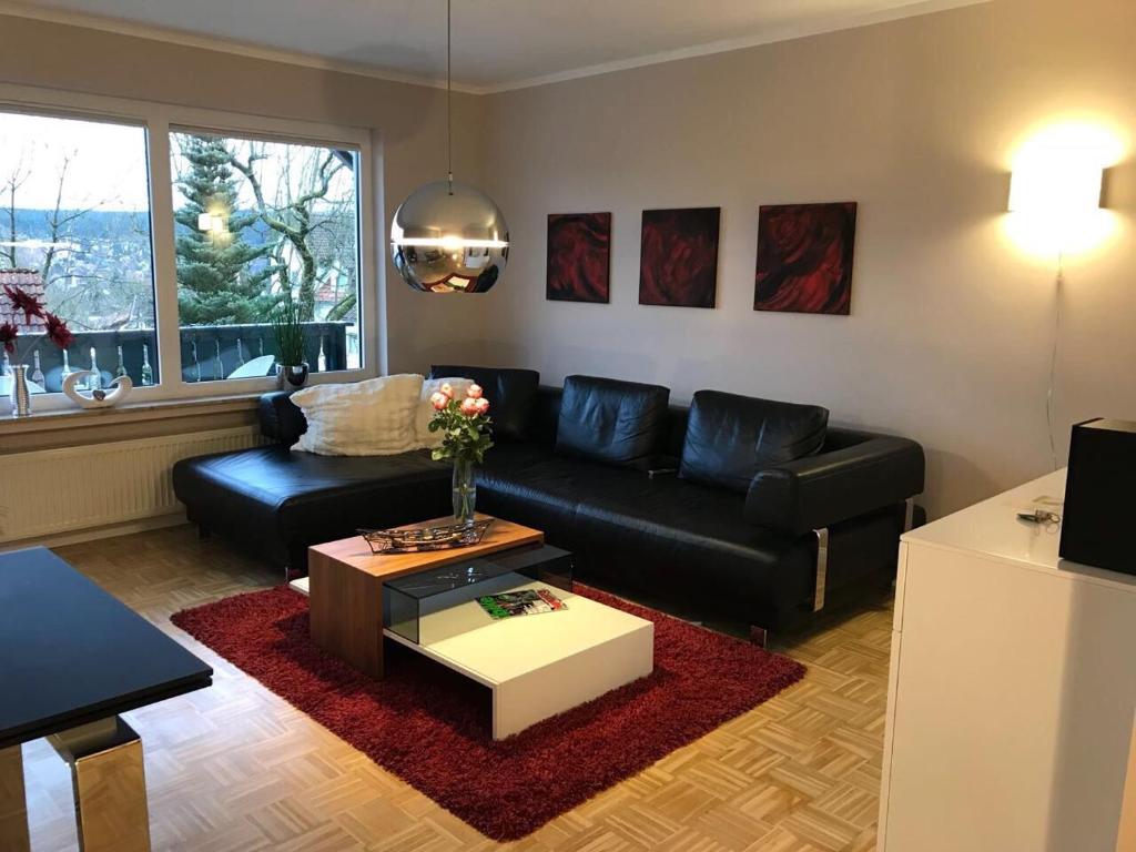 a living room with a black couch and a coffee table at Ferienwohnung Gipfelnest in Braunlage