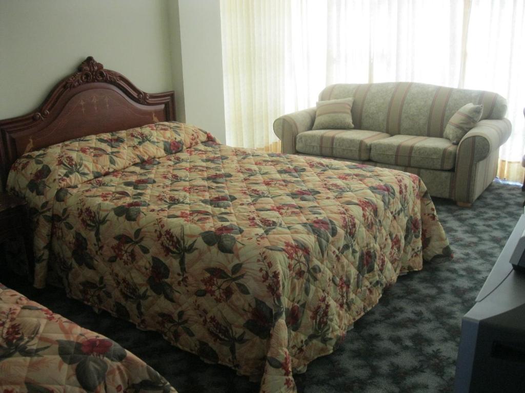 een slaapkamer met een bed en een bank bij Hotel Eden By Bluebay in Oruro