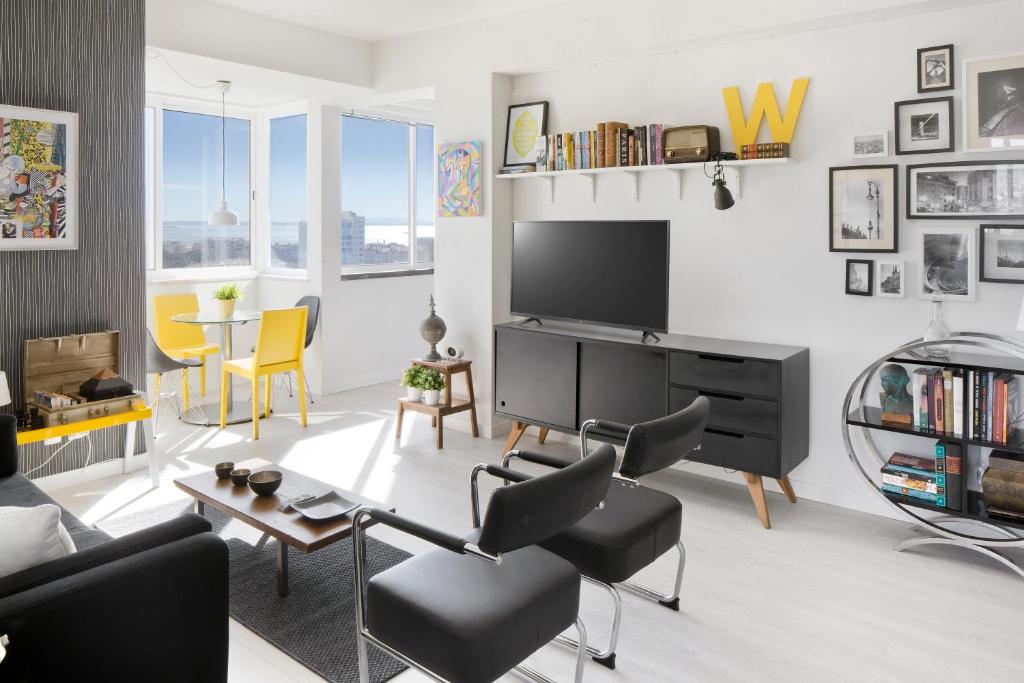 uma sala de estar com uma televisão, cadeiras e uma mesa em Prime Apartment em Cascais