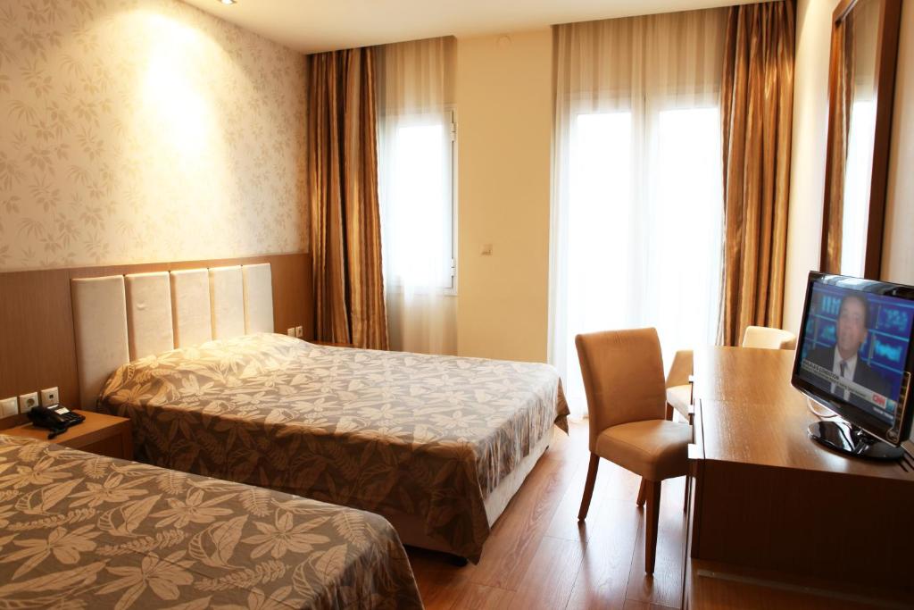 a hotel room with two beds and a desk and a television at Hotel Alfa in Edessa