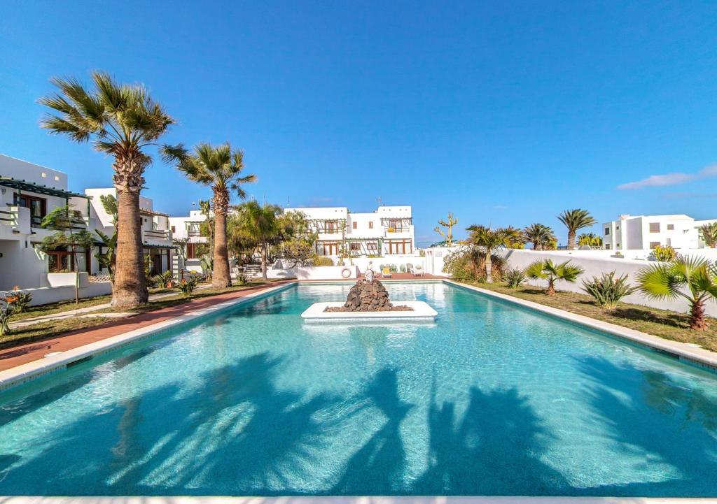 a large swimming pool with palm trees and buildings at B13-Dúplex luminoso+ piscina a 150 m del mar in Charco del Palo