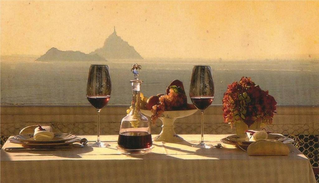 a table with two glasses of wine and a chicken on it at Gîte La Bertichère in Saint-Jean-le-Thomas