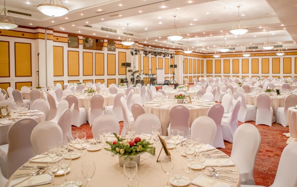 a banquet hall with white tables and white chairs at Caro Hotel in Bucharest